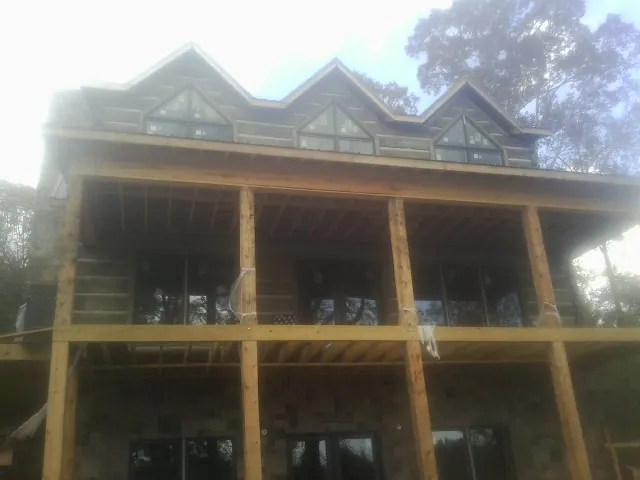 Dormers and porch framing on a large log home under construction — Roof Coating work by our crew in Antioch