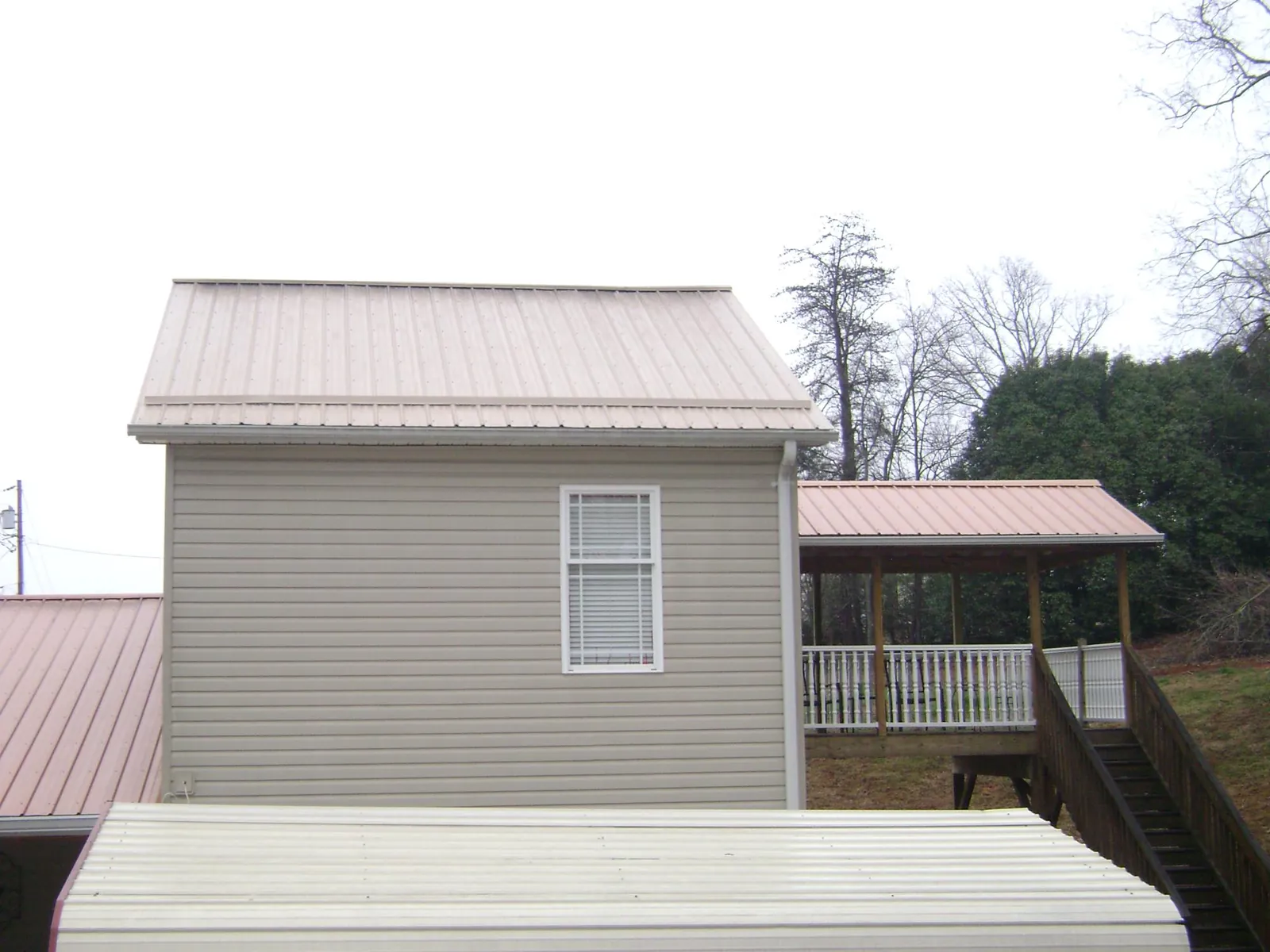 Tan metal roofs on a two story addition and attached porch, from a Roof Replacement job in Antioch