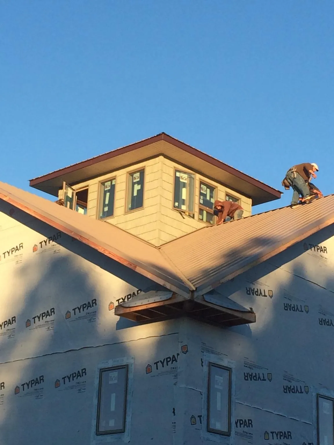 Roofers working around a rooftop cupola on a new metal roof at sunset — Roof Waterproofing in Antioch by Roofing Brothers